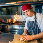 A student preparing a burger in The Wharncliffe Restaurant kitchen
